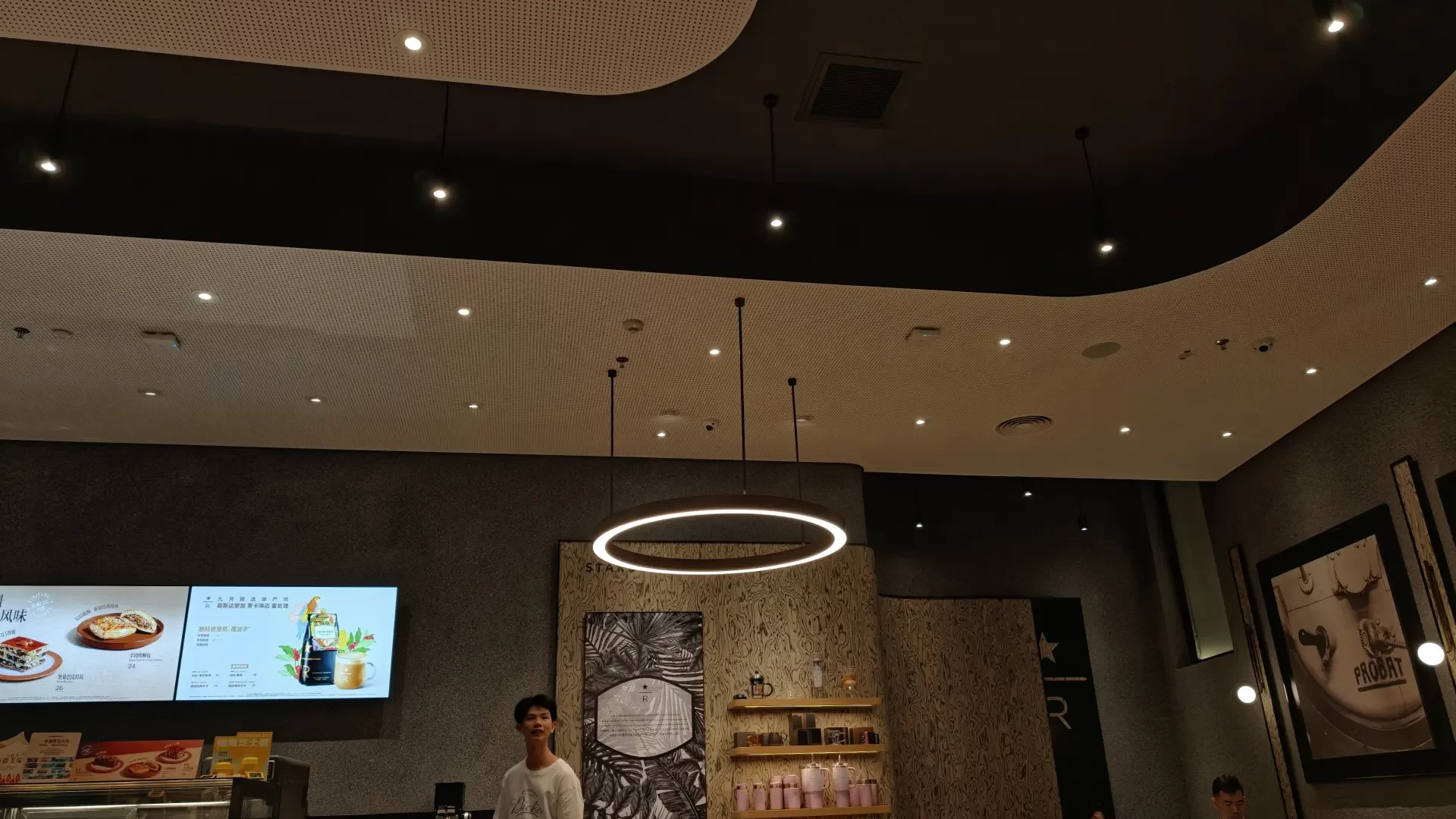 Circular linear pendant lights paired with recessed downlights in a Starbucks restaurant interior