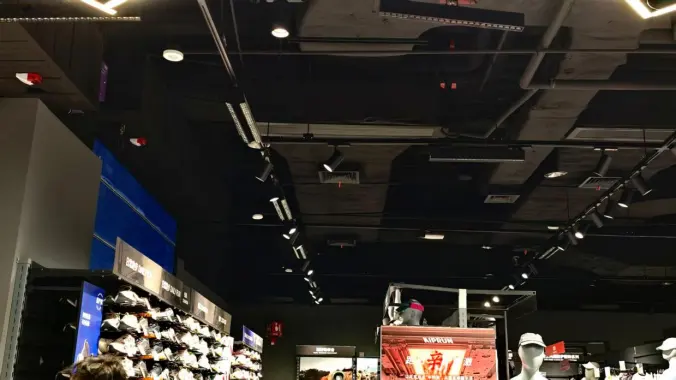 Double-line LED track grille lights illuminating retail displays from different directions