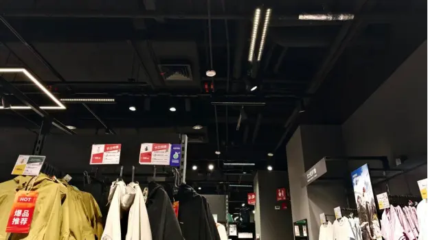 Combination of LED track spotlights and grille linear lights for layered retail lighting at Decathlon
